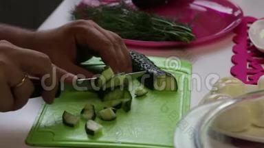 一个人从盘子里拿出一根黄瓜，然后开始在切割板上切割。