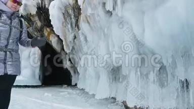 贝加尔湖冰上女子旅行。 去冬岛旅行。 女孩走在冰岩脚下。 旅行者看着