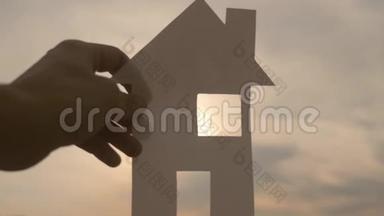 幸福家园建设理念.. 一个男人手里拿着一个纸房子，他的生活方式手里拿着夕阳剪影