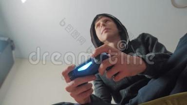 男孩少年在引擎盖上玩电子游戏的控制台上的游戏。 年轻人的生活方式带帽毛衣