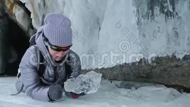 贝加尔湖冰上女子旅行。 去冬岛旅行。 女孩走在冰岩脚下。 旅行者看着
