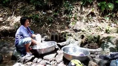 菲律宾农村社区缺乏公共供水系统设施，迫使这名妇女即使在污染的河流中也要洗衣服。