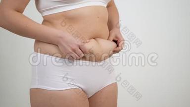 穿白色内衣的女人抱着她的腹部脂肪。