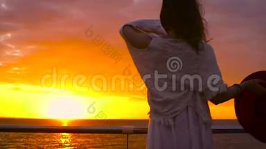 美丽的日落时分，穿着白色连衣裙和戴着帽子的年轻迷人女子在海上背景<strong>下摆</strong>姿势