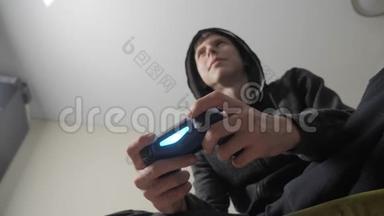 男孩少年在引擎盖上玩电子游戏的控制台上的游戏。 青少年穿着带帽子的生活方式毛衣