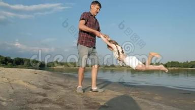 爸爸和女儿一起玩耍的特写镜头。 一位年轻的父亲正在海边给他的女儿纺纱