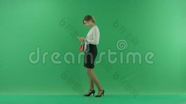 带着购物袋的漂亮购物女人。 女购物者拿着购物袋，侧着绿色背景在工作室。