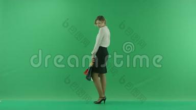 带着购物袋的漂亮购物女人。 女购物者拿着购物袋，侧着绿色背景在工作室。