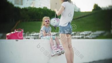 妈妈和女儿骑着溜冰鞋。 女孩学习溜冰，摔倒。 妈妈教女儿骑车