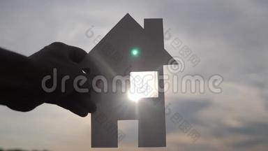 幸福家园建设理念.. 一个男人抱着一个纸房，他的手在夕阳下剪影