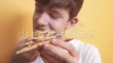 快乐的小男孩吃一片披萨的概念。 少年男孩饿了吃一片披萨。 慢动作视频。 披萨饼