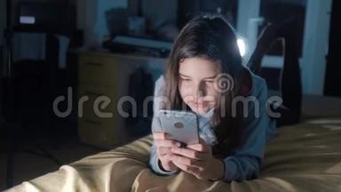 少女和智能手机。 晚上，一个小少女在社交媒体上<strong>留言</strong>聊天