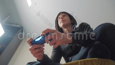 少年在引擎盖上玩电子游戏的生活方式控制台上的游戏。 少年穿着头罩毛衣