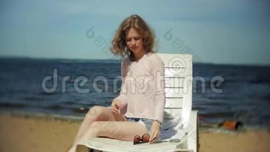 年轻女孩躺在<strong>海边</strong>沙滩上的躺椅上<strong>晒太阳</strong>