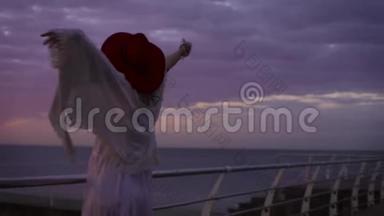 美丽的日落时分，穿着白色连衣裙和戴着帽子的<strong>年轻</strong>迷人<strong>女子</strong>在海上背景下<strong>摆姿势</strong>