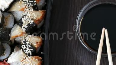 时尚的寿司放在黑色的木制背景上，旁<strong>边</strong>是酱油和<strong>中国</strong>竹签。 各种寿司卷