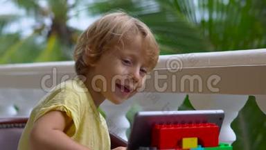 热带地区的男孩用平板电脑和无线耳机通过视频通话与<strong>朋友</strong>和<strong>家人</strong>交谈