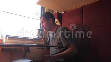 男人坐在<strong>火车车厢</strong>里，手里拿着咖啡和茶。 慢动作视频。 男人在喝茶