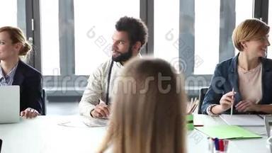 商务人士坐在会议室的桌子旁聆听演讲