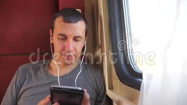 男子听音乐在火车上旅行，火车<strong>车厢车厢</strong>旅行。 慢动作视频。 一个男人