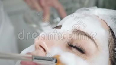 年轻漂亮的女人在美容院接受治疗。 年轻漂亮的黑发女人在办公室美容师