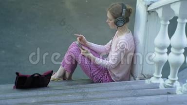 年轻时尚的美女，在城市街道上听音乐的大监控耳机。