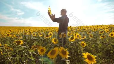 男子农民手捧一瓶葵花籽油在夕阳下的生活方式。 农民农业塑料瓶