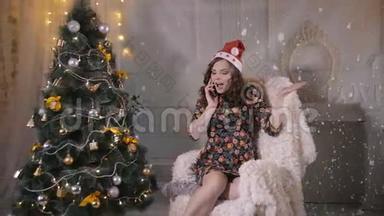 年轻可爱的英俊女孩在圣诞树附近用<strong>手机</strong>说话。 圣诞<strong>节</strong>庆典。
