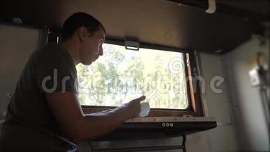 这个人坐在生活方式上，火车车厢里拿着智能手机，喝着咖啡和茶。 慢动作