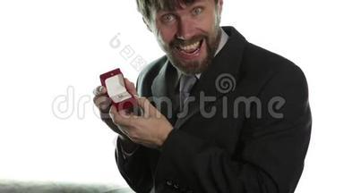 穿着商务服的<strong>大胡子</strong>男人在红盒子里戴上戒指，表达不同的情感