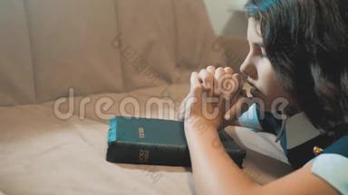 小女孩在夜里祈祷。 小女孩用手祈祷。 小女孩手里拿着圣经祈祷