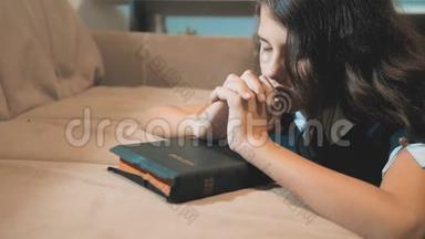 小女孩在夜里祈祷。 小女孩用手祈祷。 小女孩圣经祈祷与圣经在她的手中。 (a)