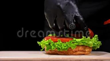 汉堡在黑色背景下用黑色食物手套做饭。 非常美味的空气面包和大理石牛肉。 餐厅