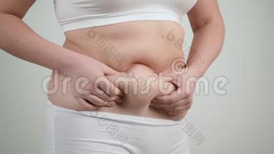 穿白色内衣的女人抱着她的腹部脂肪。