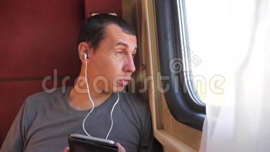 男人听着生活方式的音乐在火车车厢车厢上旅行。 慢动作视频。 一个男人