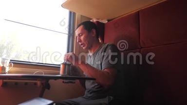 男人坐在火车车厢里，手里拿着咖啡和茶。 慢动作视频。 男人在喝茶