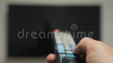 男人的生活方式手握电视遥控器，关掉智能电视。 频道冲浪。 紧紧抓住男人手里拿着电视