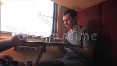 男人坐在<strong>火车车厢</strong>上，手里拿着智能手机铁路，喝着咖啡和茶。 慢动作视频。 男人