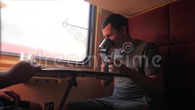 男人坐在<strong>火车车厢</strong>上，手里拿着智能手机铁路，喝着咖啡和茶。 慢动作视频。 男人