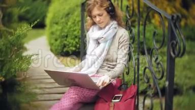有笔记本电脑的女人在一个美丽的绿色公园的长凳上放松。 一个常年在树洞里工作的年轻女人