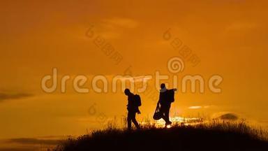 两个男子游客徒步旅行者剪影去山上日落旅游慢动作视频.. 旅行成功的年轻人
