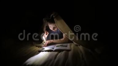小女孩正在一个黑暗的房间里用手电筒在毯子下面看书