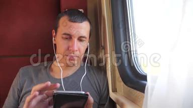 男子听音乐在火车上旅行，火车车厢车厢旅行。 慢动作视频。 一个男人