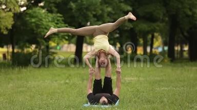 漂亮的一对<strong>练习</strong>杂技瑜伽。 年轻的瑜伽教练在绿草如茵的城市公园<strong>练习</strong>。 两次成功