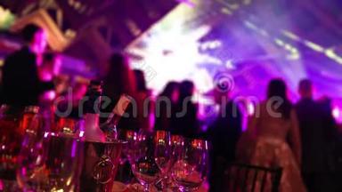 在餐馆或夜总会举行的青年聚会，在剪影的背景下摆满酒和食物的宴会桌