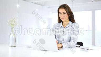 办公室里忙着用笔记本电脑工作的严肃女人