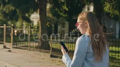 一位年轻女士走路和使用智能手机
