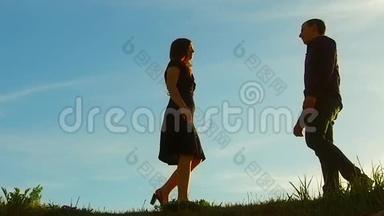 日落时分一对夫妇的剪影。 男人和女人的剪影在夕阳下缓慢的运动。 日出时情侣接吻