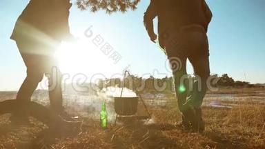 两名游客啤酒正坐在篝火徒步聚会上，在大自然中露营<strong>剪影</strong>，阳光日落。 两个<strong>剪影</strong>