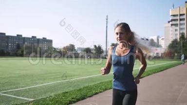 健身女运动员在体育场跑道上跑步
